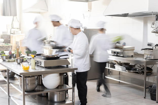 Hotel kitchen layout with chefs working around stainless steel prep stations and commercial cooking equipment.
