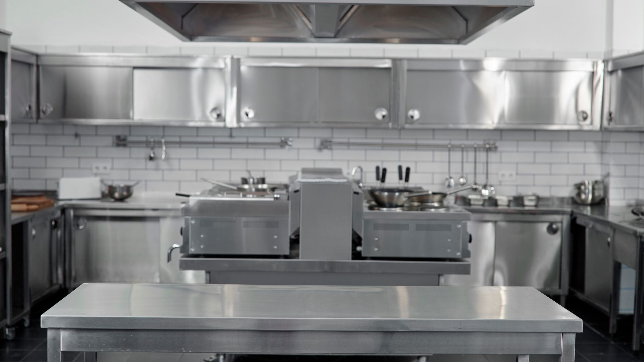 Empty professional kitchen with stainless steel appliances and workstations, representing stainless steel commercial kitchen equipment.