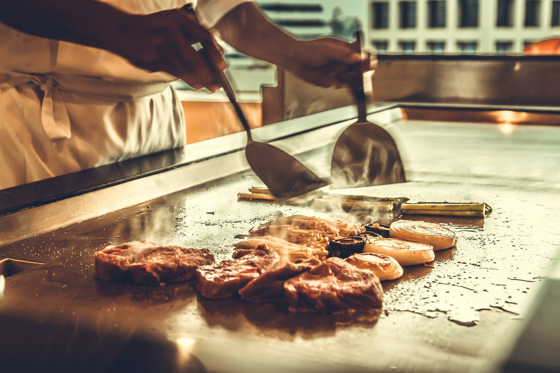 Chef cooking on a commercial griddle in a professional restaurant kitchen.