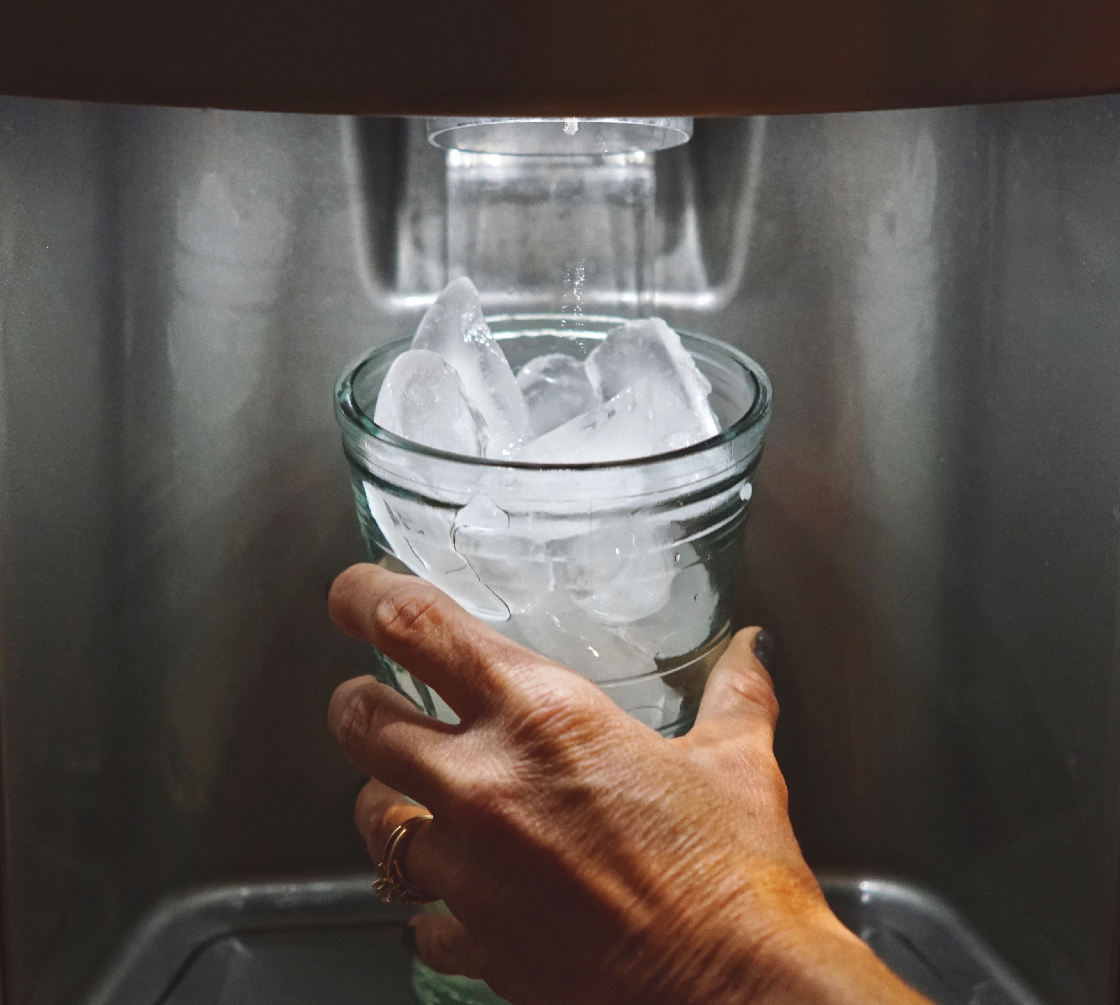 A commercial ice maker dispensing ice into a glass, demonstrating the importance of water quality for reliable ice production.
