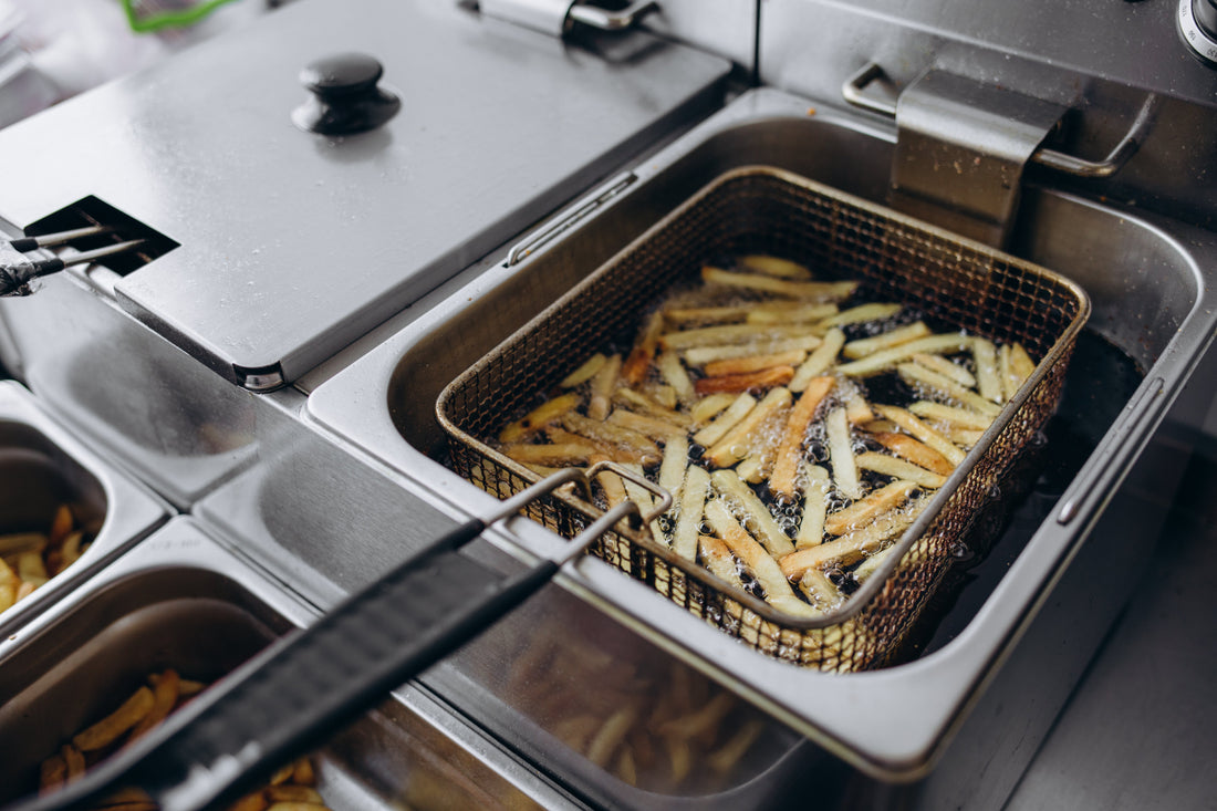 French fries cooking in a commercial deep fat fryer in a professional kitchen.