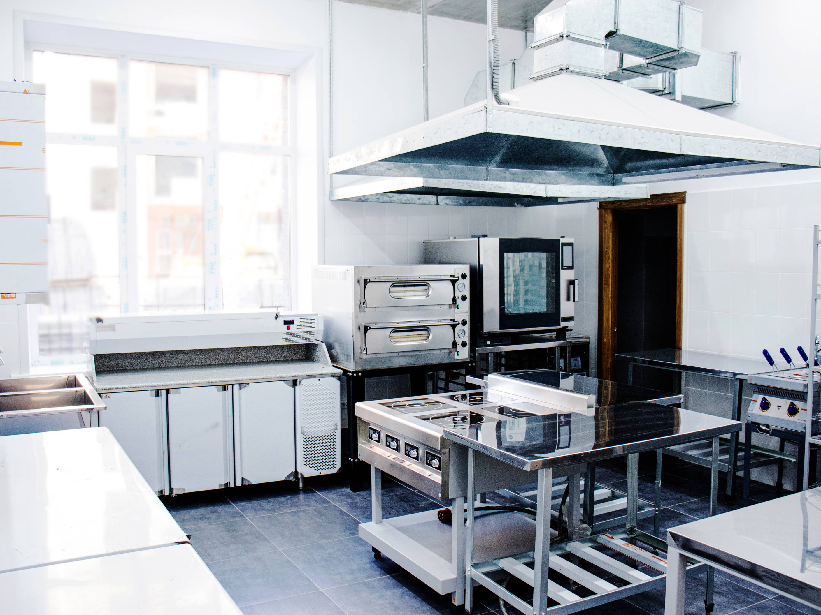 Modern commercial kitchen with stainless steel cooking stations, representing essential equipment in a commercial kitchen for restaurants.