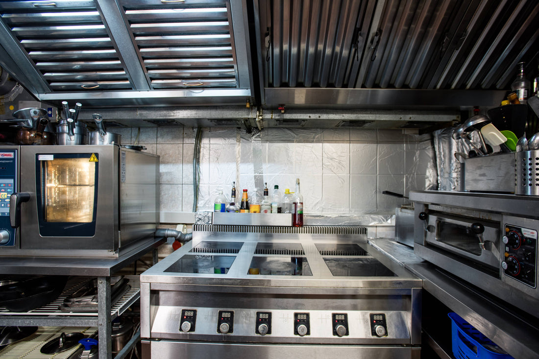 Commercial kitchen staff working around professional cooking stations, representing kitchen equipment for restaurant service and operations.