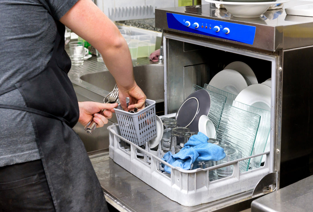Staff loading a commercial dishwasher in a professional kitchen to improve cleaning efficiency and hygiene.