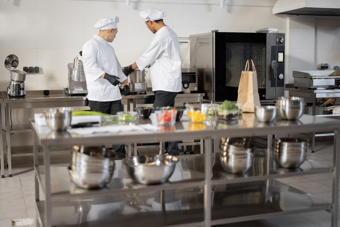 Chefs using commercial catering equipment in a professional kitchen to prepare food efficiently.